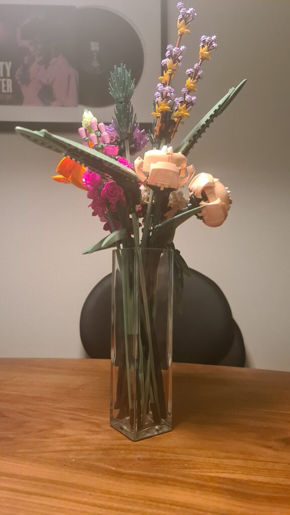 A bouquet of flowers on a table, the flowers are made of Lego pieces.